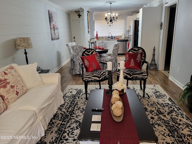 living room featuring hardwood / wood-style flooring, an inviting chandelier, crown molding, and sink