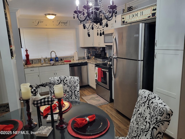 kitchen with sink, dark hardwood / wood-style floors, light stone countertops, appliances with stainless steel finishes, and white cabinetry