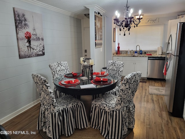 dining area with dark hardwood / wood-style floors, sink, crown molding, and an inviting chandelier