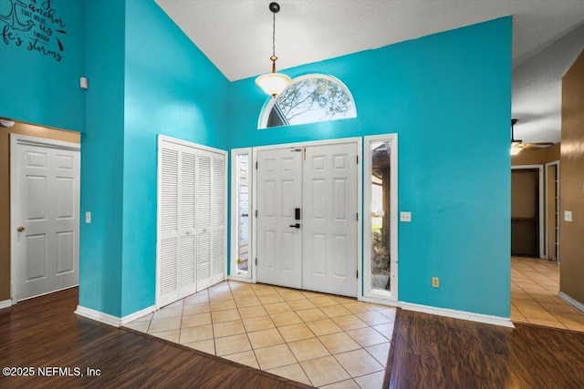 foyer entrance with high vaulted ceiling, ceiling fan, and light hardwood / wood-style flooring