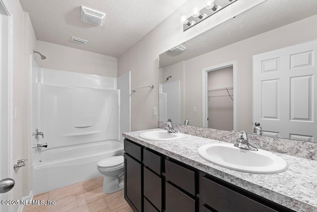 full bathroom featuring vanity, tile patterned flooring, toilet, a textured ceiling, and tub / shower combination