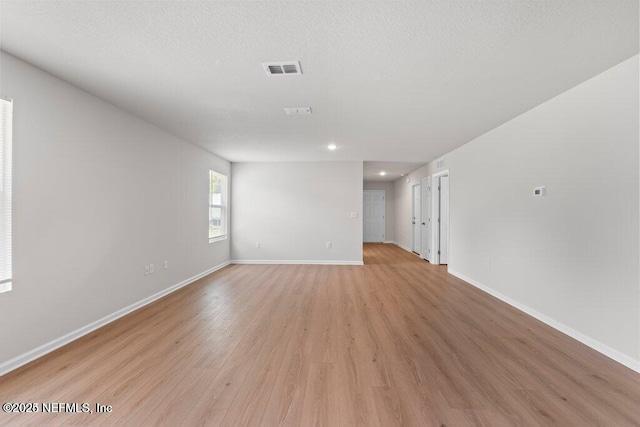 empty room with a textured ceiling and light hardwood / wood-style floors