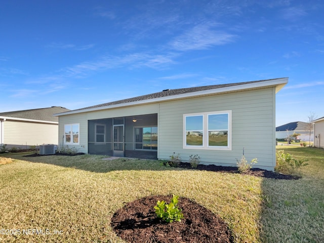 rear view of property with a yard, central air condition unit, and a sunroom