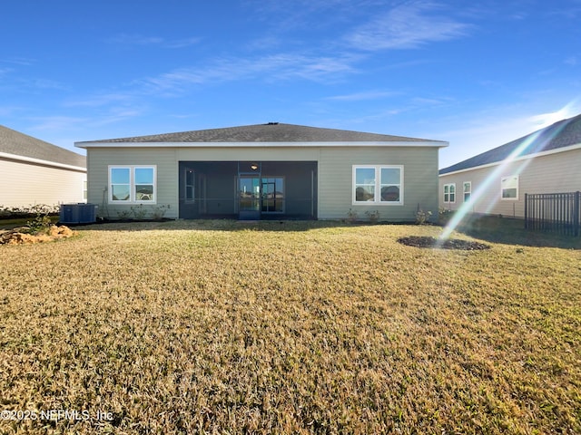 back of property featuring central AC unit, a lawn, and a sunroom