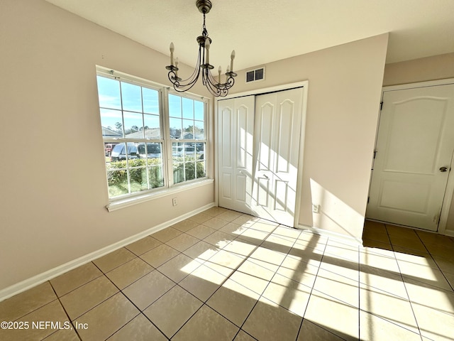 unfurnished dining area with a notable chandelier and light tile patterned flooring