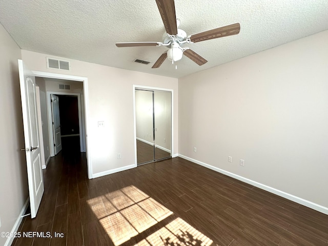 unfurnished bedroom featuring ceiling fan, dark hardwood / wood-style flooring, a textured ceiling, and a closet