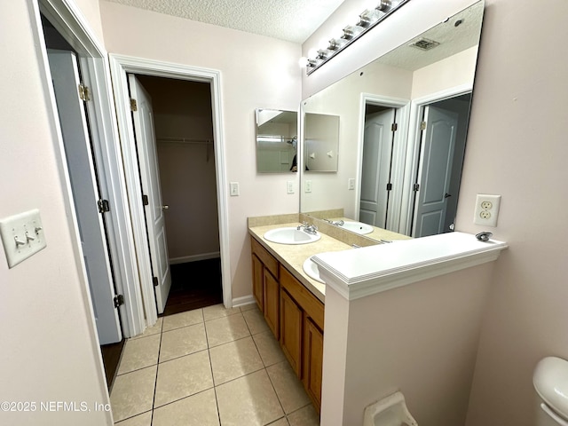 bathroom with vanity, a textured ceiling, tile patterned floors, and toilet