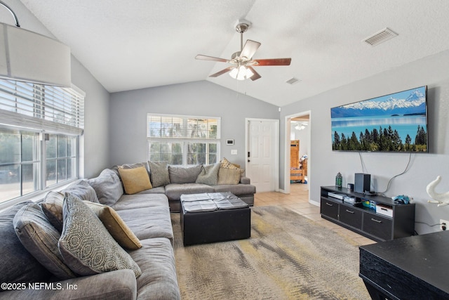 tiled living room featuring a textured ceiling, ceiling fan, and lofted ceiling