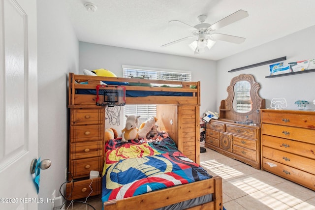 bedroom with ceiling fan, light tile patterned floors, and a textured ceiling