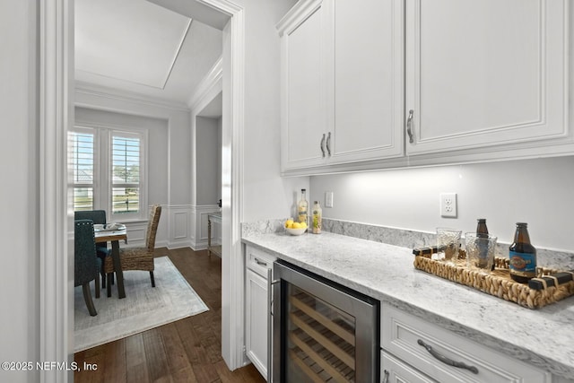 bar featuring white cabinets, crown molding, light stone counters, dark hardwood / wood-style flooring, and beverage cooler