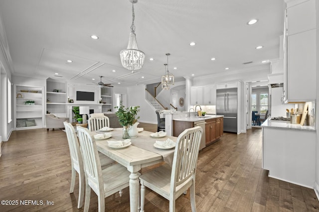 dining room with crown molding, dark hardwood / wood-style flooring, built in features, and ceiling fan with notable chandelier