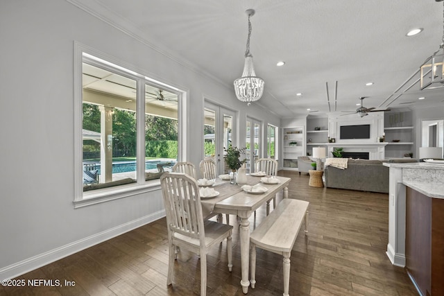 dining area featuring dark hardwood / wood-style floors, built in features, ceiling fan with notable chandelier, and ornamental molding