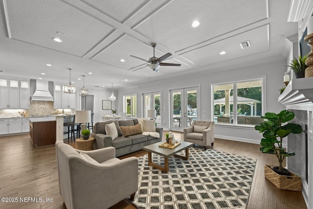 living room with french doors, dark hardwood / wood-style flooring, coffered ceiling, ceiling fan, and crown molding