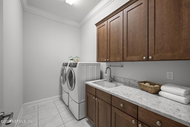 clothes washing area featuring cabinets, a textured ceiling, crown molding, sink, and washing machine and dryer