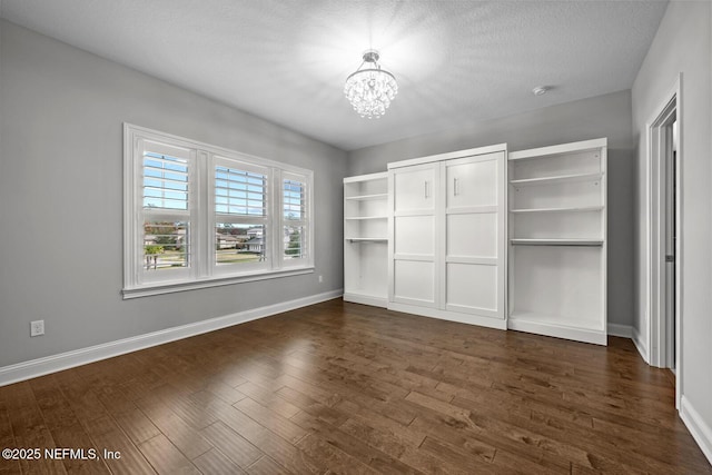 unfurnished bedroom featuring dark hardwood / wood-style flooring, a textured ceiling, and an inviting chandelier