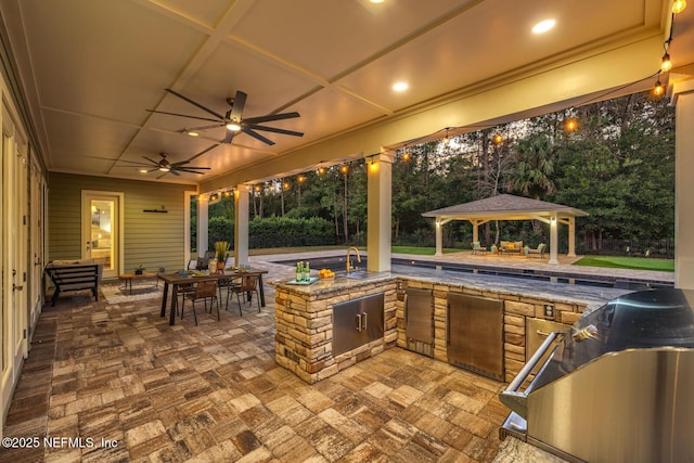 view of patio / terrace featuring a gazebo, ceiling fan, exterior kitchen, and sink