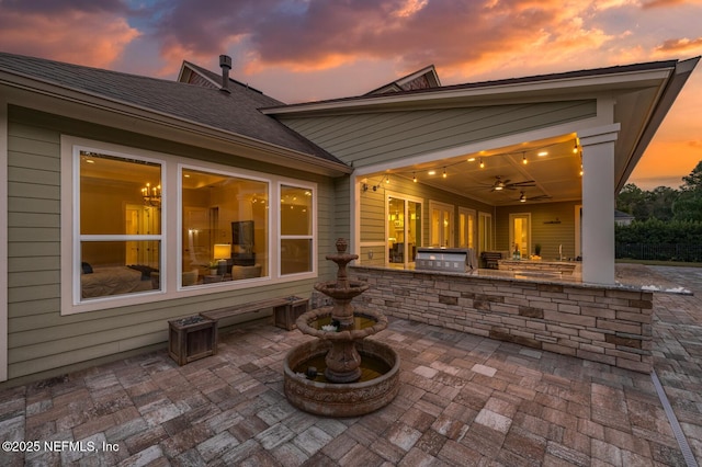 patio terrace at dusk featuring exterior kitchen