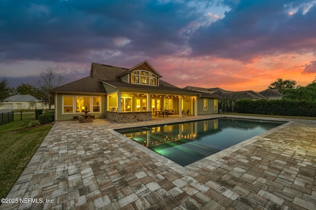 back house at dusk with a fenced in pool and a patio