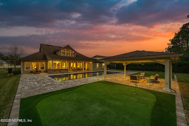 back house at dusk with a patio area and an outdoor living space with a fire pit