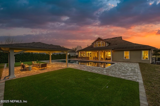 back house at dusk featuring an outdoor living space, a yard, and a patio