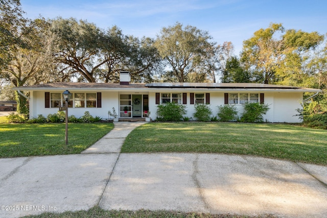 single story home with solar panels, covered porch, and a front yard