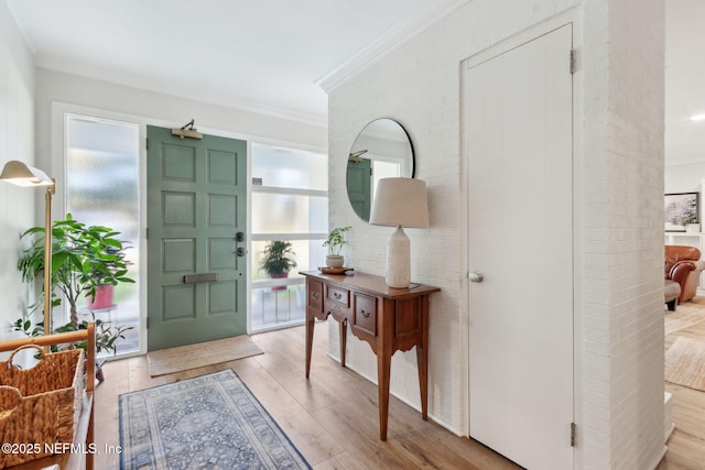 entrance foyer with ornamental molding and light hardwood / wood-style flooring