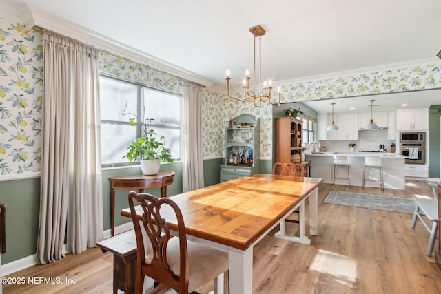 dining room with ornamental molding, light hardwood / wood-style floors, and an inviting chandelier