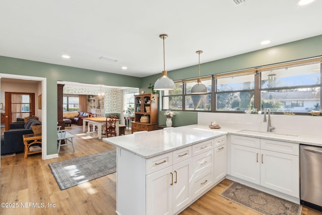 kitchen with dishwasher, white cabinets, sink, hanging light fixtures, and light stone countertops