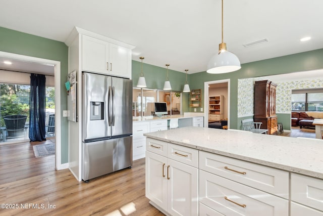 kitchen with pendant lighting, light hardwood / wood-style flooring, stainless steel fridge with ice dispenser, light stone countertops, and white cabinetry