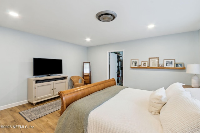 bedroom featuring a spacious closet and light hardwood / wood-style flooring