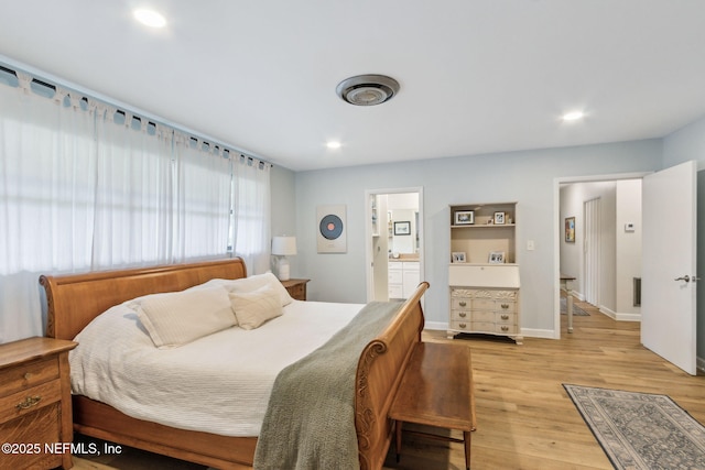 bedroom with ensuite bathroom and light hardwood / wood-style flooring