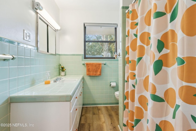 bathroom with vanity, toilet, tile walls, curtained shower, and wood-type flooring