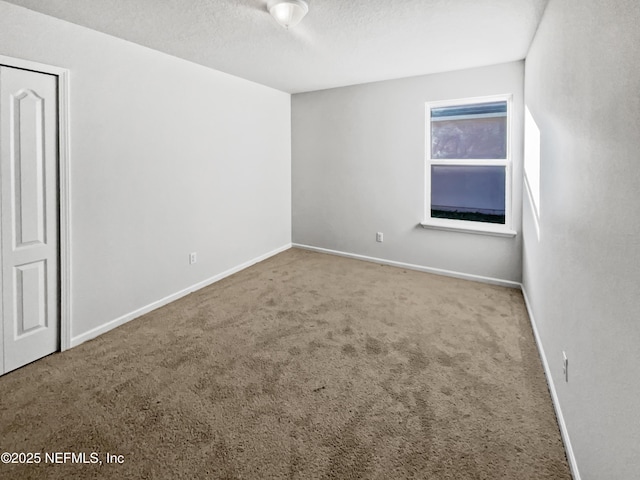 carpeted empty room featuring a textured ceiling