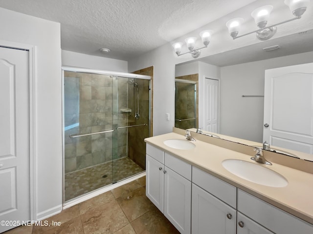 bathroom featuring vanity, a shower with door, and a textured ceiling