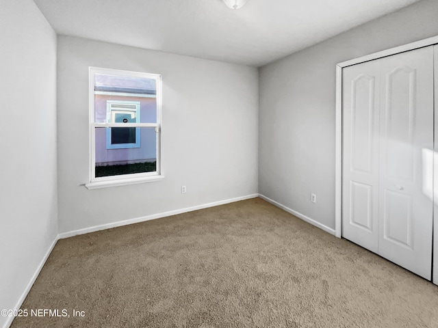 unfurnished bedroom with light carpet and a closet