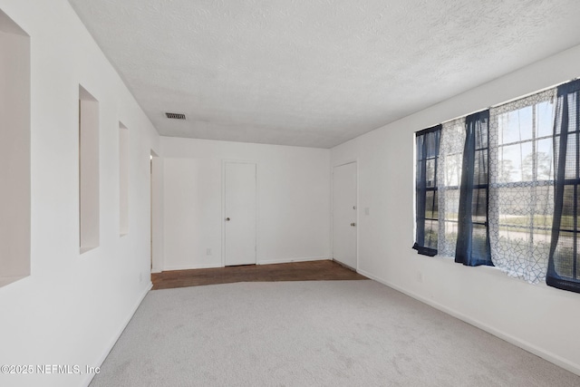 unfurnished room with carpet and a textured ceiling