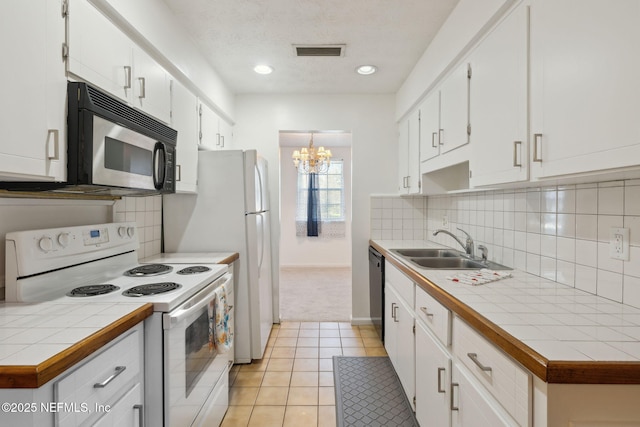 kitchen with tile countertops, light carpet, an inviting chandelier, black appliances, and white cabinets