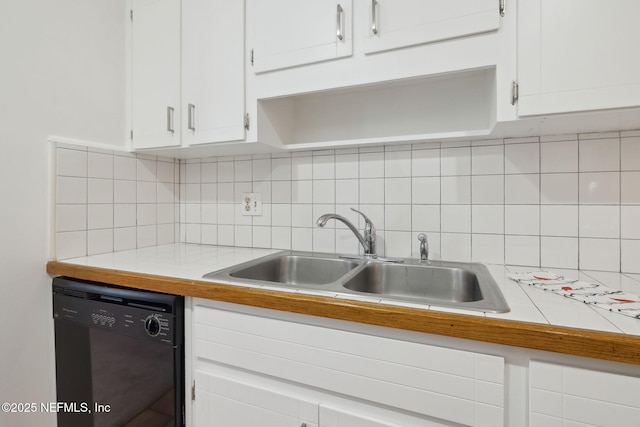 kitchen featuring white cabinets, sink, black dishwasher, and tasteful backsplash