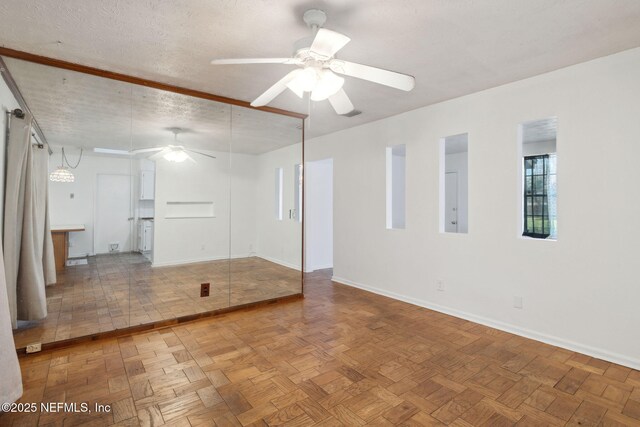 unfurnished room with ceiling fan, parquet floors, and a textured ceiling