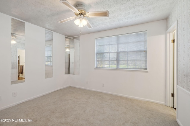 unfurnished room featuring a textured ceiling, light colored carpet, and ceiling fan