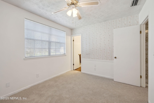 unfurnished bedroom with light carpet, a textured ceiling, and ceiling fan