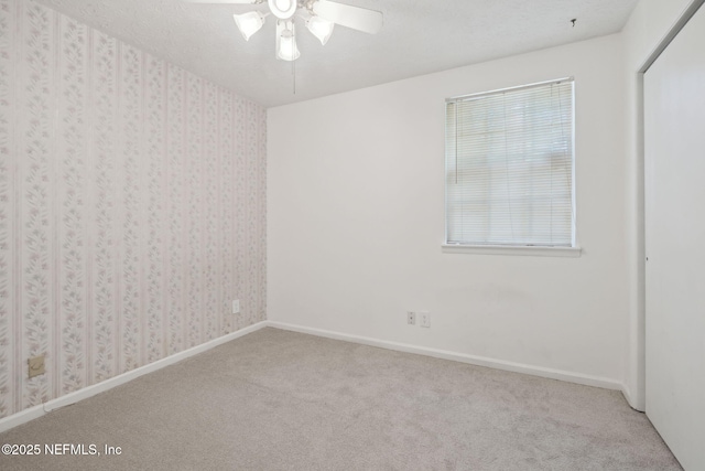 carpeted spare room featuring ceiling fan