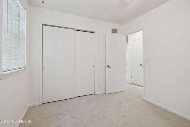 unfurnished bedroom with light colored carpet and a closet