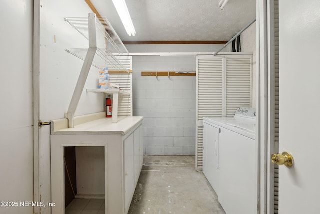 clothes washing area featuring a textured ceiling and washer and clothes dryer