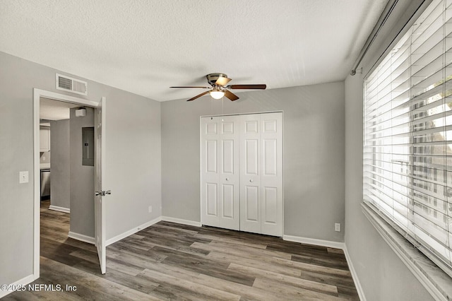 unfurnished bedroom with multiple windows, ceiling fan, a closet, and dark wood-type flooring