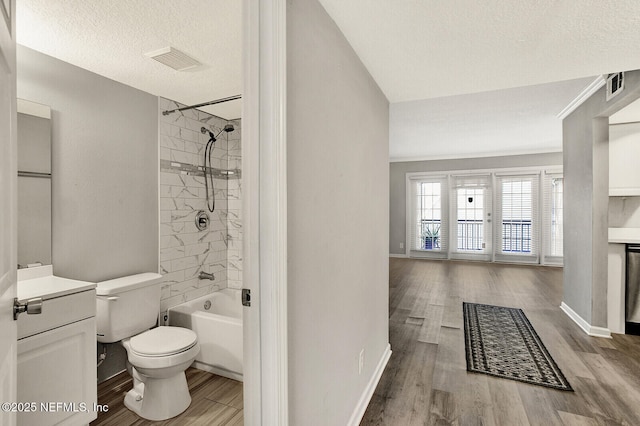 full bathroom with toilet, tiled shower / bath combo, a textured ceiling, and hardwood / wood-style flooring