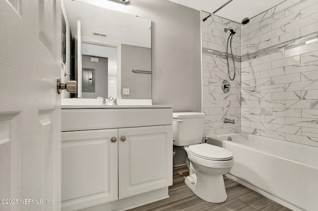 full bathroom featuring tiled shower / bath combo, toilet, wood-type flooring, and vanity