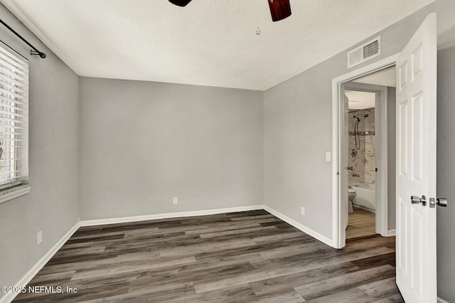 unfurnished bedroom featuring ceiling fan, a textured ceiling, and dark wood-type flooring