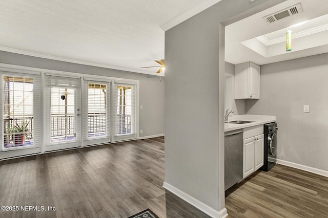 kitchen with crown molding, stainless steel dishwasher, dark hardwood / wood-style floors, white cabinetry, and washer / clothes dryer