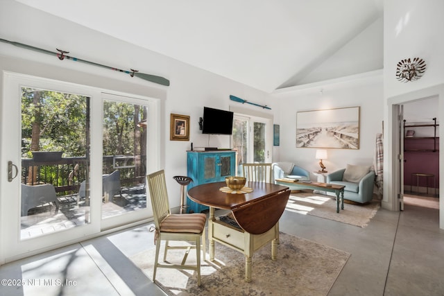 dining space with concrete flooring, french doors, and high vaulted ceiling